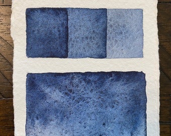 May include: A rectangular piece of textured white paper featuring the handwritten text "Shaolow Blue" at the top. Below the text are three small blue watercolor squares showing a gradient, and a larger blue watercolor rectangle at the bottom.