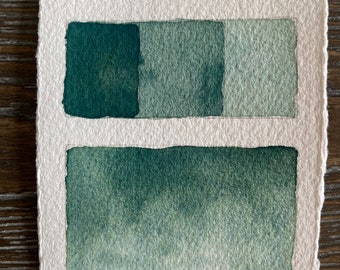 May include: A watercolor paint swatch card with the text "Hosta Green" written at the top. The card shows three shades of green, from dark to light, and a gradient of green.