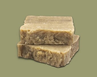 May include: Two bars of brown soap stacked on top of each other. The soap has a rough, textured surface.