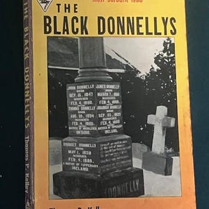 Pu&ograve; includere: Un libro tascabile vintage intitolato "The Black Donnellys" con una copertina gialla e arancione. La copertina presenta una fotografia di una lapide e una croce. Il libro &egrave; un libro Harlequin di Thomas P. Kelley.
