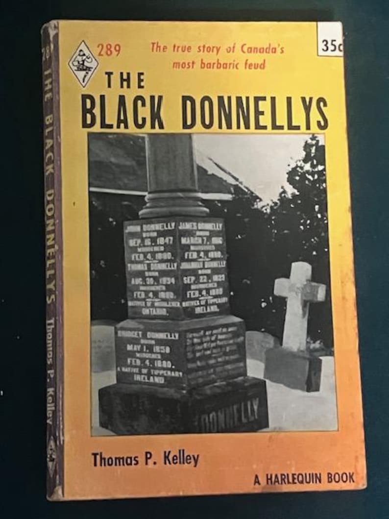 Pu&ograve; includere: Un libro tascabile vintage intitolato "The Black Donnellys" con una copertina gialla e arancione. La copertina presenta una fotografia di una lapide e una croce. Il libro &egrave; un libro Harlequin di Thomas P. Kelley.