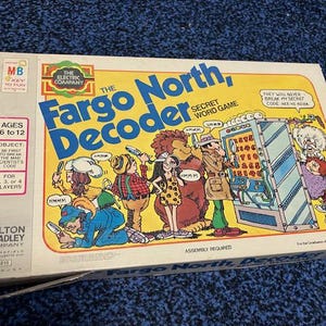 May include: A vintage board game box for Fargo North, Decoder. The box features a colorful illustration of cartoon characters and a secret code machine. The game is for 2-4 players and is recommended for ages 6-12.