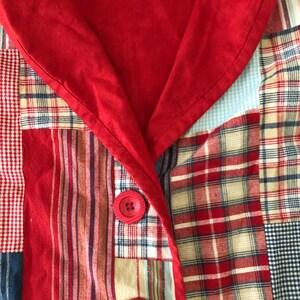 Peut inclure: Un v&ecirc;tement au motif patchwork compos&eacute; de divers tissus &agrave; carreaux, rayures et vichy dans des tons rouge, blanc et bleu. Il pr&eacute;sente un col rouge uni et deux boutons rouges ronds et textur&eacute;s sur la fermeture avant, cr&eacute;ant un aspect vari&eacute;.