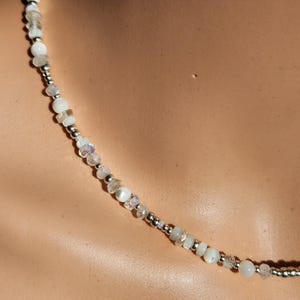 May include: A white and silver beaded necklace with iridescent stones.