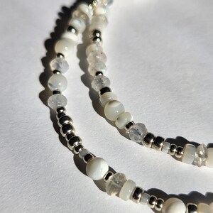 May include: A white beaded necklace with silver beads and moonstone beads.