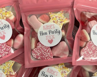 May include: Multiple pink resealable pouches filled with assorted gummy candies, including star-shaped, heart-shaped, and round pieces. Each pouch features a circular white sticker printed with the text Katie's Hen Party 22.8.26 and a small pink heart.