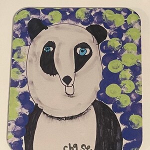 May include: A rectangular coaster with a hand-painted panda bear illustration. The panda has black and white fur, blue eyes, and the word "chase" is written at the bottom. The background features blue and green circular patterns.