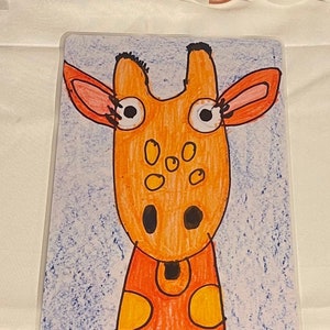 May include: A rectangular, clear plastic tray featuring a colorful, cartoon giraffe illustration. The giraffe has an orange body with yellow spots, large eyes, and a blue background. The giraffe's head is orange with black accents.