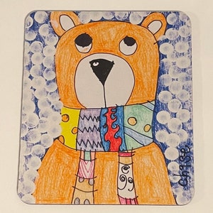 May include: A colorful, hand-drawn illustration of a bear with a patterned scarf. The bear is orange with a black nose and eyes, and the scarf features yellow, blue, red, and green designs. The background is blue with white circles.