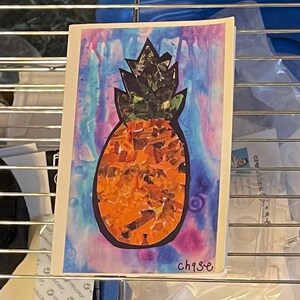 Könnte beinhalten: Ein farbenfroher Kunstdruck mit einer Ananas. Die Ananas ist orange und braun, mit einer dunkelgrünen und schwarzen Krone. Der Hintergrund ist eine Aquarellwaschung aus Blau, Lila und Rosa. Der Druck hat den Text "ch93e" in der unteren rechten Ecke.