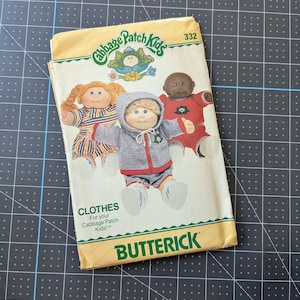 May include: A vintage Butterick sewing pattern for Cabbage Patch Kids clothes. The pattern cover features illustrations of three Cabbage Patch Kids dolls wearing different outfits. The pattern number is 332.