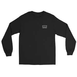 May include: Black long-sleeve t-shirt with a small white crown graphic on the left chest.