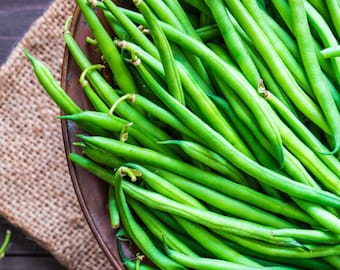 May include: A close-up of a bowl filled with fresh, green string beans. The beans are arranged in a random pattern, showcasing their vibrant color and smooth texture.
