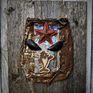 Puede incluir: Un letrero de metal oxidado con una estrella roja, dos conchas negras y un pez de dibujos animados marrón con una aleta. El letrero está unido a una superficie de madera.