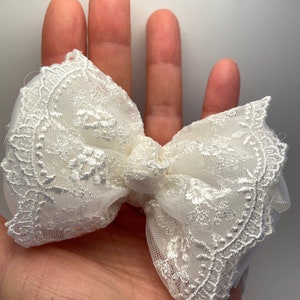 Puede incluir: Un lazo blanco de encaje con un delicado patr&oacute;n floral. El lazo est&aacute; hecho de una tela suave y transparente, perfecto para agregar un toque de elegancia a cualquier atuendo.