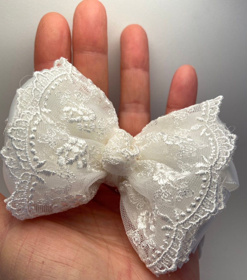 Puede incluir: Un lazo blanco de encaje con un delicado patr&oacute;n floral. El lazo est&aacute; hecho de una tela suave y transparente, perfecto para agregar un toque de elegancia a cualquier atuendo.