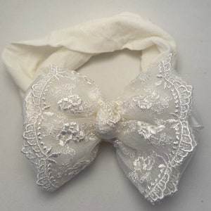 Puede incluir: Diadema blanca con un gran lazo blanco de encaje. El lazo est&aacute; hecho de una tela transparente con un delicado bordado floral.