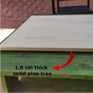 May include: Close-up of a light wood tabletop, showing the grain of the wood. The tabletop is 1.8 cm thick and made of solid pine tree.