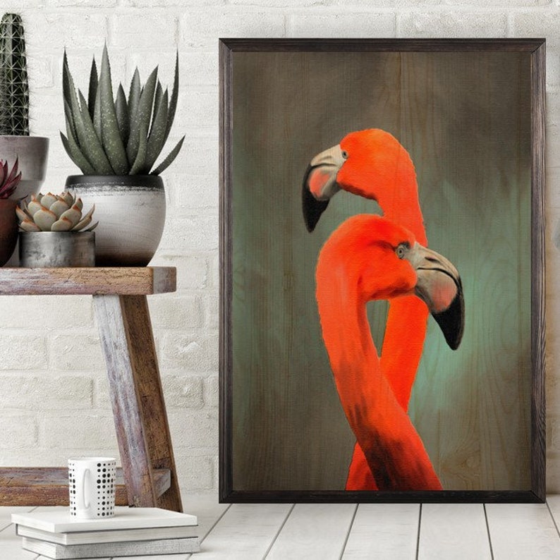 May include: A framed print of two pink flamingos with their necks intertwined, set against a textured wood background.
