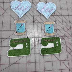 May include: Embroidered patches featuring sewing-themed designs. The image shows two light blue heart-shaped patches with the text "Loved Sew Much", two teal thread spools, and two green sewing machine patches with the text "Sewciopath".