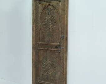 May include: A carved wooden door with intricate designs. The door is brown and has a dark wood finish. The door is closed and has a metal handle.