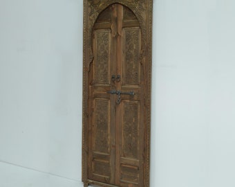 May include: A carved wooden door with an arched top and intricate details. The door is made of two panels and has a dark brown finish.