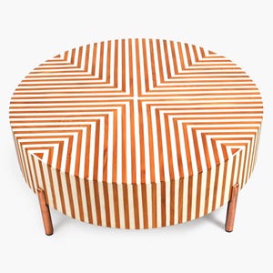 Peut inclure: Table basse ronde avec un plateau rayé blanc et marron et des pieds en cuivre. Le plateau présente un motif géométrique de rayures.