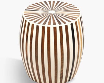 May include: A decorative wooden stool with a circular top and a barrel-shaped body. The top features a sunburst pattern, while the sides have vertical stripes in shades of brown and cream. This accent furniture piece is suitable for any room.