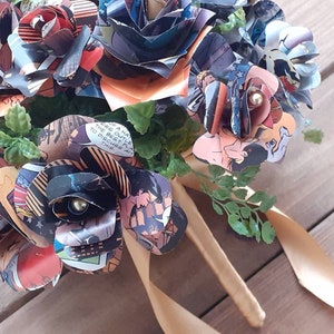 May include: A bouquet of paper roses made from comic book pages. The roses are tied together with a gold ribbon and have small pearl accents.