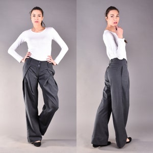 May include: A pair of wide-leg, charcoal gray pants with a high waist and pleats. The pants have a button closure and a zipper fly.
