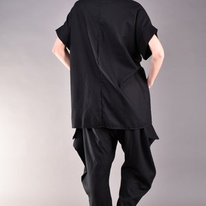 May include: A black, loose-fitting shirt with a high neck and short sleeves, paired with black pants that have a gathered design at the ankles.