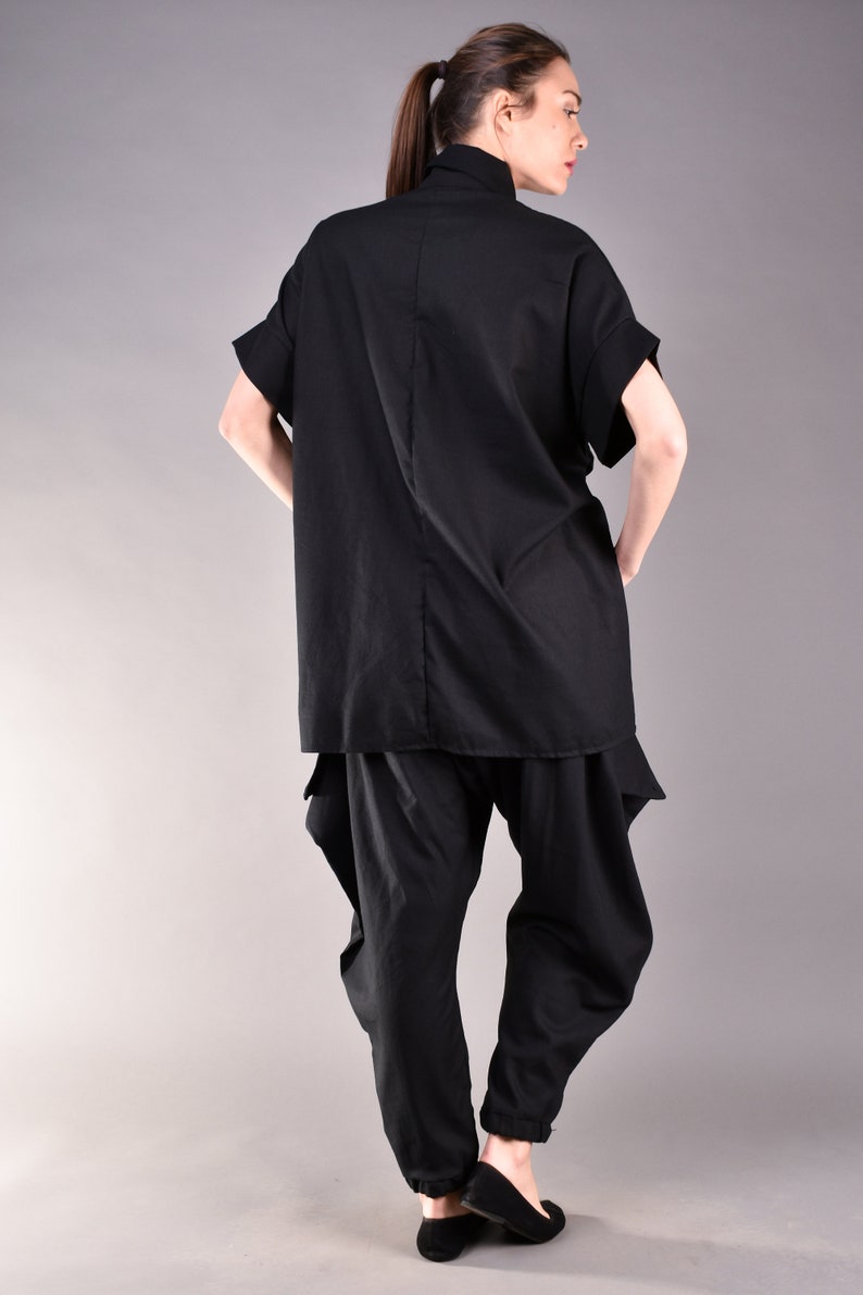 May include: A black, loose-fitting shirt with a high neck and short sleeves, paired with black pants that have a gathered design at the ankles.