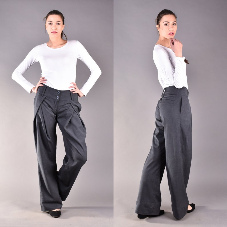 May include: A pair of wide-leg, charcoal gray pants with a high waist and pleats. The pants have a button closure and a zipper fly.