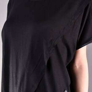 May include: Black short-sleeved t-shirt with a diagonal seam detail and a black leather panel at the bottom.
