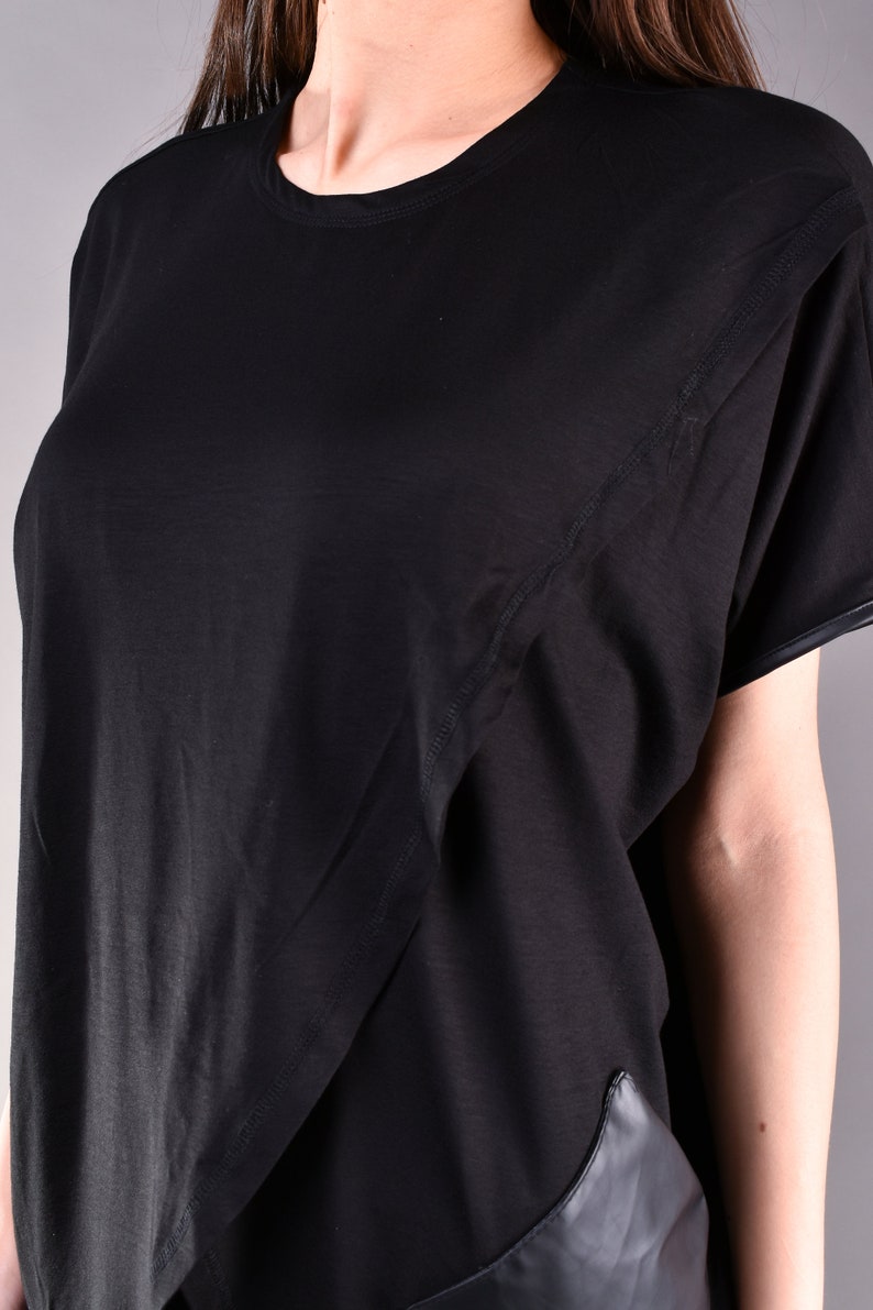 May include: Black short-sleeved t-shirt with a diagonal seam detail and a black leather panel at the bottom.