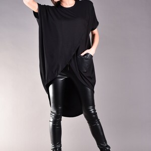 May include: A black, long-sleeved shirt with a high-low hemline and a faux leather pocket. The shirt is paired with black leather leggings and black combat boots.