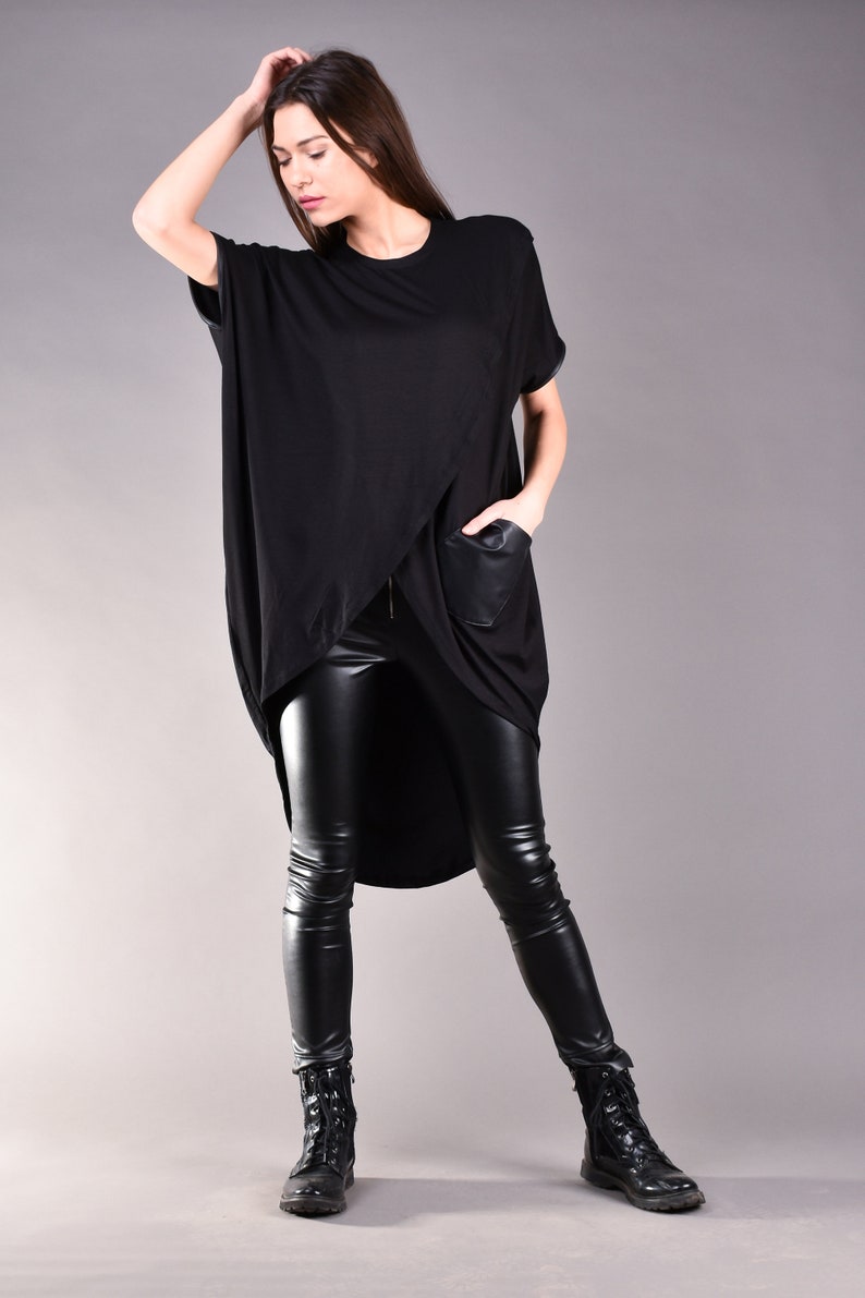 May include: A black, long-sleeved shirt with a high-low hemline and a faux leather pocket. The shirt is paired with black leather leggings and black combat boots.