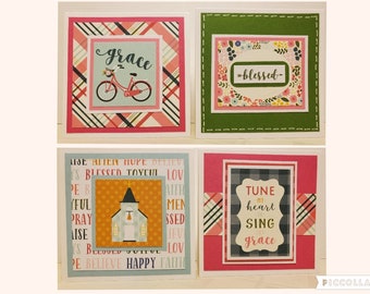 May include: Four handmade greeting cards with different designs. The first card has a pink bicycle with flowers on a light blue background and the word "grace" written in black. The second card has a green background with a floral border and the word "blessed" written in black. The third card has a church on a yellow background with the words "tune my heart to sing grace" written in black. The fourth card has a church on a yellow background with the words "tune my heart to sing grace" written in black.