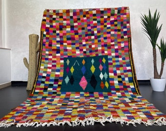 May include: A colorful Moroccan rug with a geometric pattern of squares and diamonds. The rug is made of wool and has a fringe border.