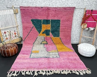 Puede incluir: Una alfombra marroquí rosa, verde, amarilla y blanca con un patrón geométrico. La alfombra tiene un borde de flecos.