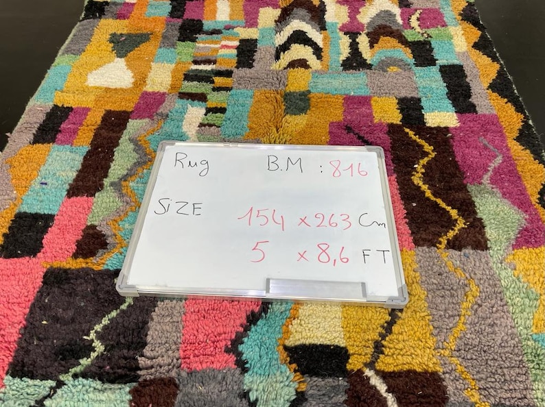 May include: A colourful rug with geometric patterns in shades of pink, blue, yellow, and brown. The rug is 1.54 metres by 2.63 metres and has a B.M. of 816.