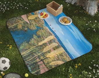 May include: A blue and yellow picnic blanket with a scenic landscape design. The blanket is spread out on green grass with a soccer ball, tennis racket, and a basket of fruit nearby.