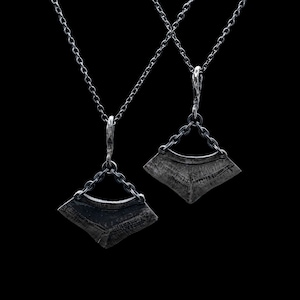 May include: Two silver necklaces with geometric pendant charms. The pendants are shaped like a fan and have a textured surface.