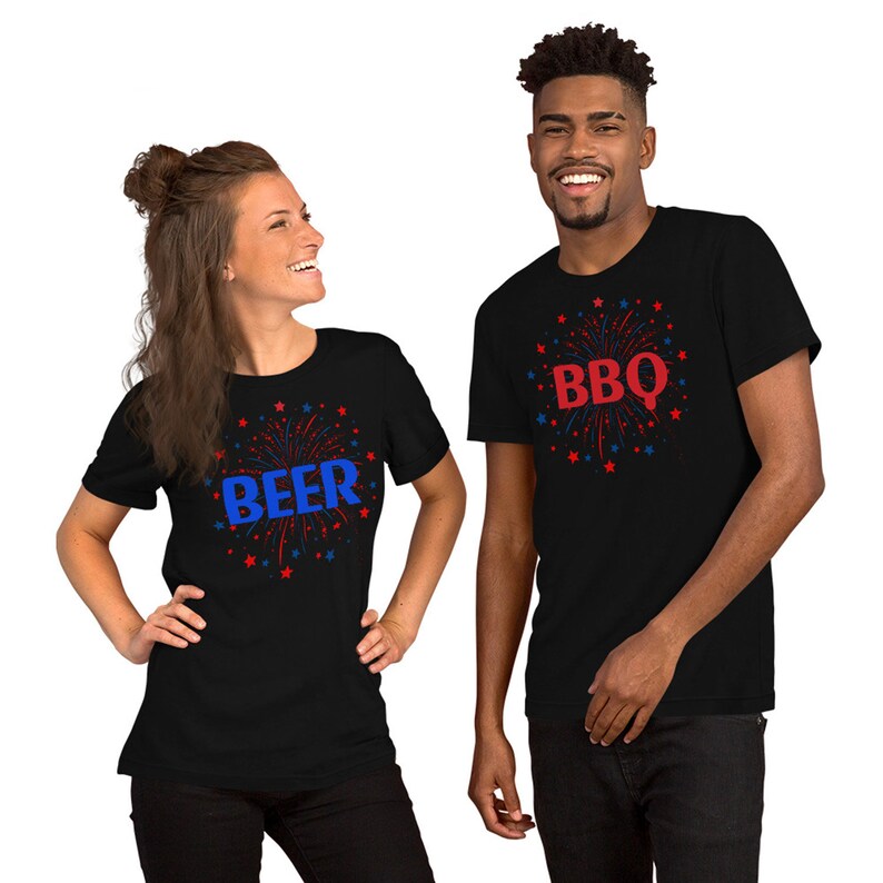 May include: Two black t-shirts with red and blue firework designs. One shirt says "BBQ" and the other says "BEER".