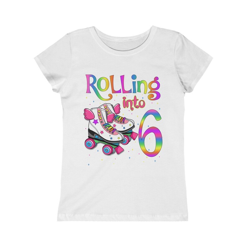 Puede incluir: Camiseta blanca con un gr&aacute;fico de arco&iacute;ris que dice "Rolling into 6" con un par de patines de ruedas de arco&iacute;ris.
