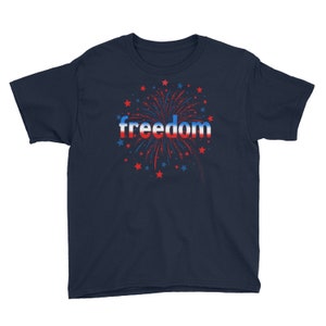 May include: Navy blue youth t-shirt with a red, white, and blue firework graphic and the word "freedom" in a red, white, and blue gradient.