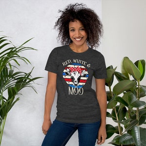 Może przedstawiać: Szary t-shirt z nadrukiem w kolorze czerwonym, białym i niebieskim, przedstawiającym amerykańską flagę z krową w czerwono-biało-niebieskiej bandanie. Na koszulce widnieje napis "Red, White & Moo".