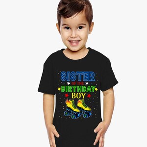 May include: Black toddler t-shirt with the text "SISTER OF THE BIRTHDAY BOY" in blue, green, and red. The shirt features a graphic of yellow roller skates with blue wheels. The design includes stars and confetti.