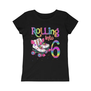 Puede incluir: Camiseta negra con un gr&aacute;fico de arco&iacute;ris que dice "Rolling into 6" con un par de patines de ruedas de arco&iacute;ris.