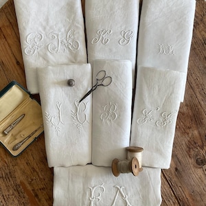 Peut inclure: Un ensemble de sept linges blancs rectangulaires, chacun orné de monogrammes brodés en blanc. Le lot comprend un petit dé à coudre en métal, une paire de ciseaux en métal noir, deux bobines de fil en bois et un petit étui contenant deux outils.